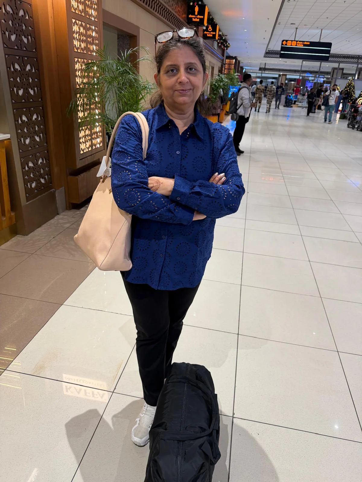 Ayush's mother standing at an airport with her luggage