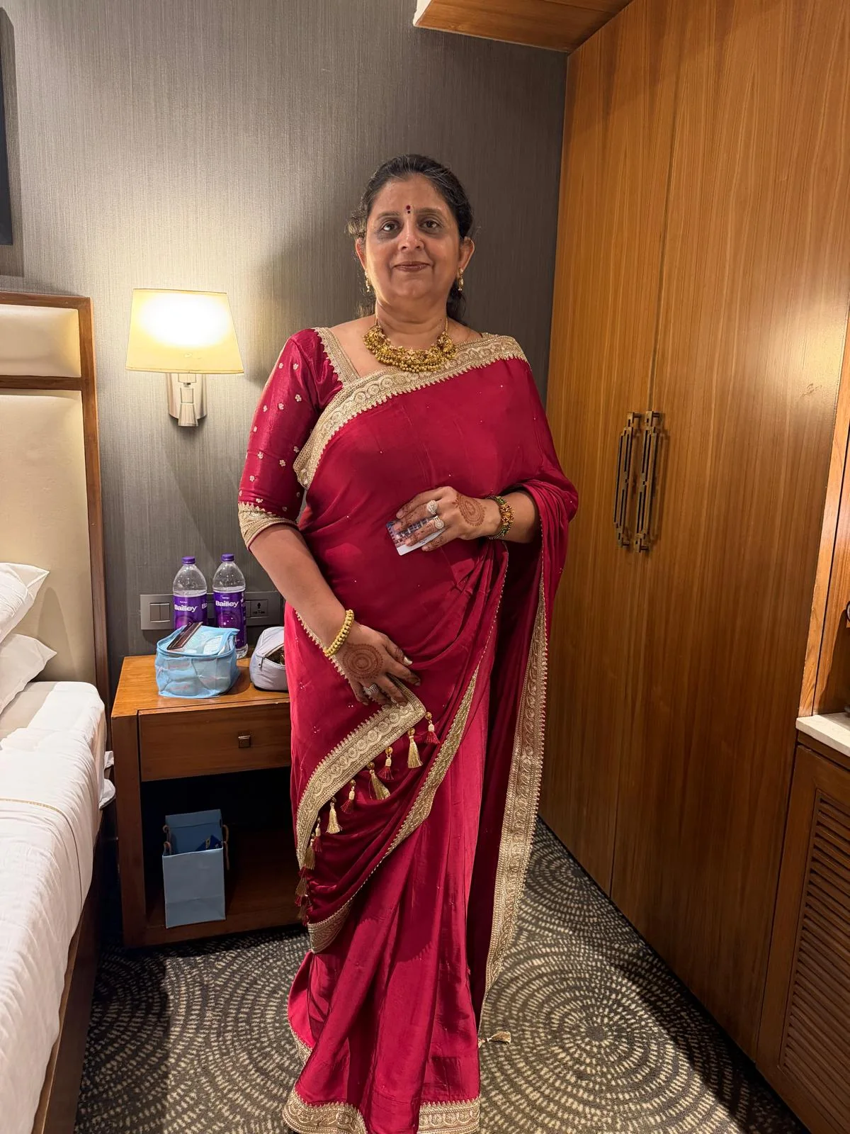 Ayush's mother dressed in an elegant red sari